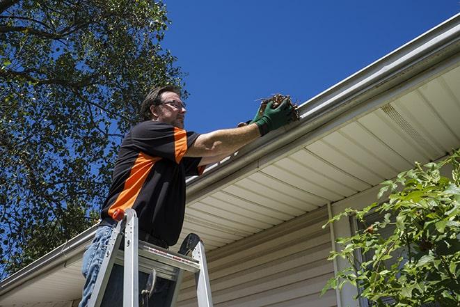 a roofer repairing a damaged gutter on a house in Cedar Lake, IN